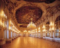 an ornate hall with chandeliers and mirrors on the walls is lit by lights