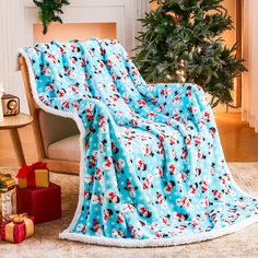 a blanket that is sitting on the floor next to a christmas tree and presents in front of it