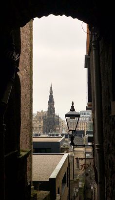 the view from an alley way looking down at a building with a clock tower in the distance