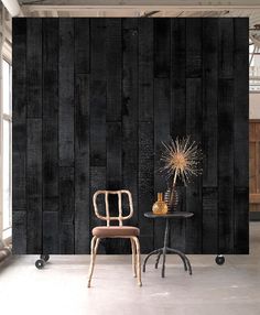 two chairs and a table in front of a black wall with wooden planks on it