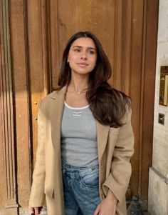 a woman standing in front of a wooden door with her hand on her hip and looking at the camera