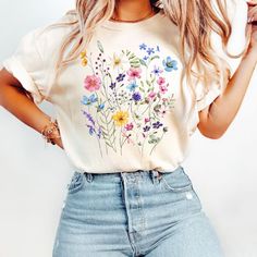 a woman with blonde hair wearing jeans and a t - shirt that has flowers on it