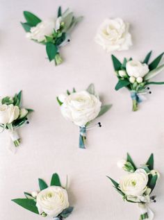 white flowers and greenery are arranged on a table