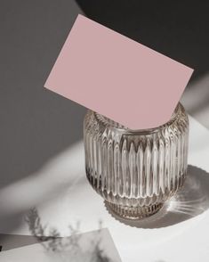 a glass vase sitting on top of a table with a pink card stuck to it