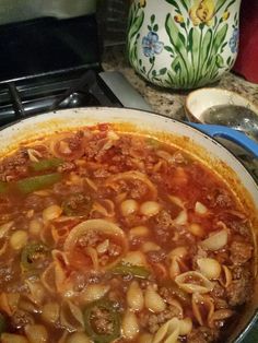 a large pot filled with pasta and meat on top of a stove next to an oven