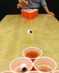 a man sitting at a table with cups on it and one person reaching for something