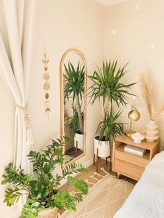 a bedroom with plants and a mirror on the wall, along with other decor items