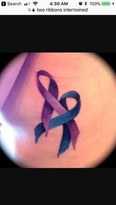 a purple and blue ribbon tattoo on the back of a woman's left shoulder