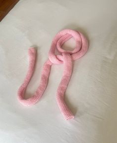 a pink scarf laying on top of a white bed