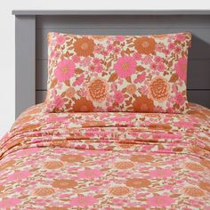 an orange and pink floral bed spread with matching pillow shampoos on the headboard