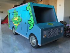 an ice cream truck is painted blue and has green designs on the side, while it's parked in a garage