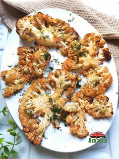 a white plate topped with fried cauliflower on top of a table