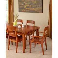 a dining room table with four chairs and a vase on the table in front of it