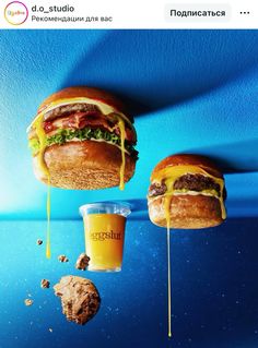 two hamburgers with cheese, lettuce and bacon on them next to a drink