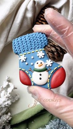 a hand holding a cookie shaped like a snowman