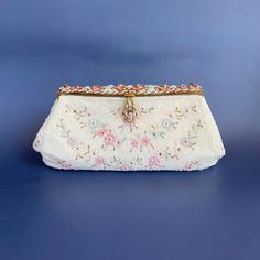 Gorgeous beaded antique evening hand bag with glass bead work of dainty flowers in white, greens, blues, and pinks.  Frame features beautiful enamel work in the same colors with further intertwined beadwork. Interior lined with ivory covered silk.  Original mirror has a scalloped bevel edge and fits perfectly tucked into the interior side pocket. Clasp is firm. Stamped inside: "Made in France. Hand Made." Early 20th century. Simply stunning. Approximate dimensions: 9" length x 4.5" height x 2" d Elegant White Evening Bag For Vintage Events, Vintage White Embellished Bags, Vintage Pearl Embroidered Evening Bag For Events, Vintage Evening Bag With Pearl Embroidery For Events, Vintage White Embellished Evening Bag, Antique Beaded Wedding Bag, Antique Beaded Wedding Bags, Vintage White Beaded Clutch, Vintage White Clutch For Events