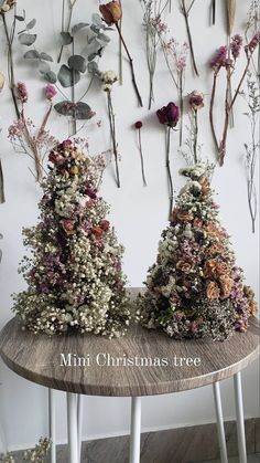 two small trees made out of flowers sitting on top of a wooden table