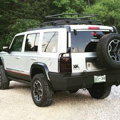 a white jeep parked on top of a gravel road