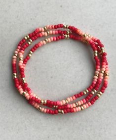 three red and gold beaded bracelets on a white surface