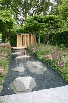 a garden with rocks and water in the center, surrounded by trees and flowers on either side