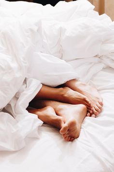 a person laying in bed with white sheets