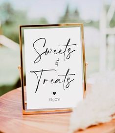 a sign that says sweets and treats is on top of a wooden table with feathers