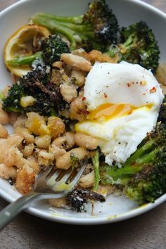 a white bowl filled with broccoli and an egg