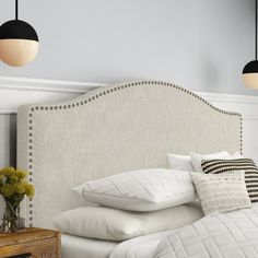 a bed with white linens and pillows in a bedroom next to two hanging lights