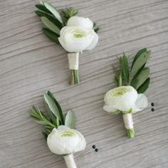 three white flowers are arranged on a table