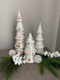 three ceramic christmas trees sitting on top of a wooden table