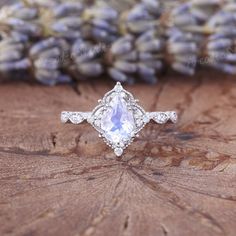 a white diamond ring sitting on top of a piece of wood next to lavender flowers