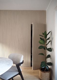 a room with a table and chairs next to a wall covered in vertical slats