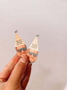 a person holding up two tiny birthday hats