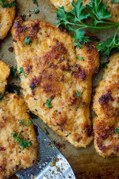 several pieces of chicken with parsley on top and a spatula next to it