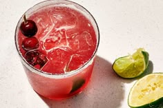 a drink with cherries and limes next to it