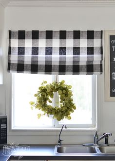 a kitchen window with a wreath hanging on it's valance above the sink