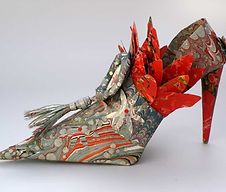 an origami shoe with red flowers on it