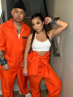 a man and woman in orange prison jumpsuits standing next to each other on stairs