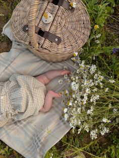 a baby laying on top of a blanket next to a wicker basket and flowers