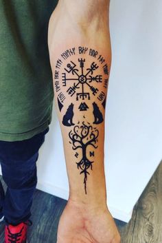 a person with a tattoo on their arm holding up a compass and two cats in the middle