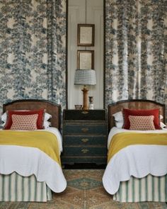 two beds in a bedroom with floral wallpaper