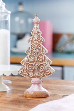 a small wooden christmas tree sitting on top of a table next to a white candle