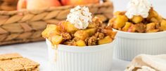 two small white bowls filled with dessert next to some crackers and apples in the background