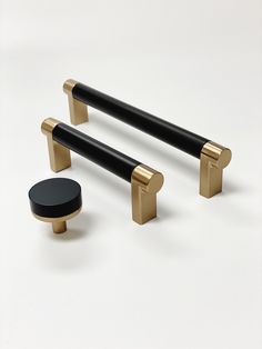 two black and gold handles on white surface with one black knob, the other brass