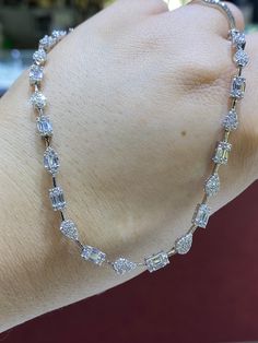 a woman's hand wearing a bracelet with clear stones on the clasp and chain