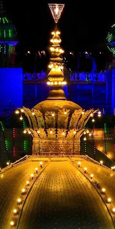 an illuminated fountain in the middle of a park at night with lights all around it