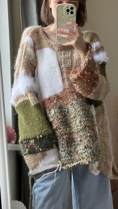 a woman taking a selfie in front of a mirror wearing a sweater and jeans