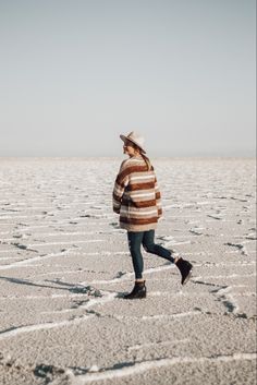 a woman walking across a salt flat covered with lots of snow and ice flakes