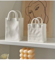 two white bags sitting on top of a shelf next to some balloons and a painting