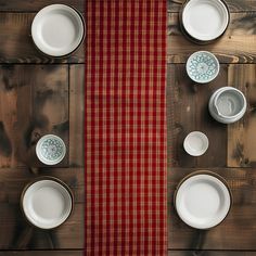 the table is set with dishes and place mats on it, along with a red plaid runner